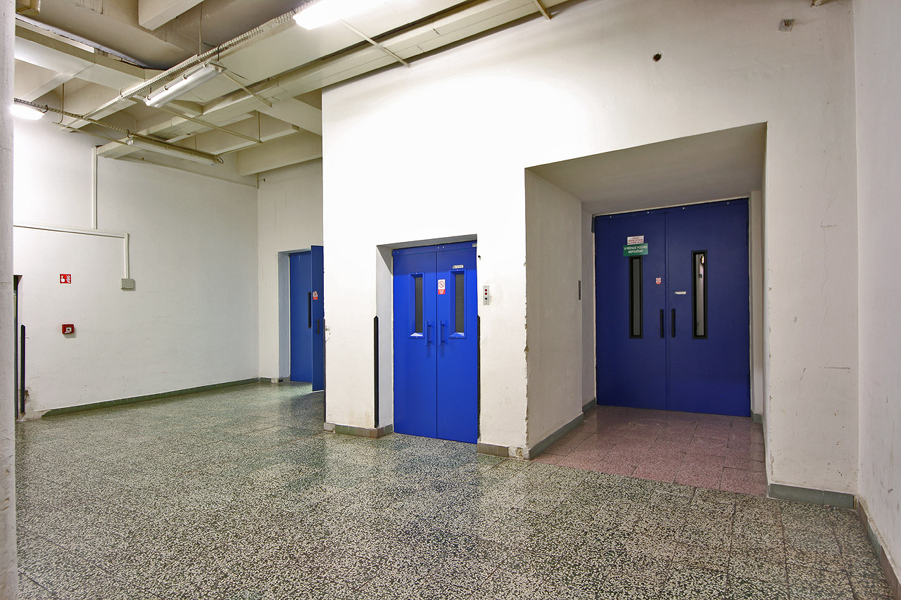 V zázemí ani při velké snaze nebylo možné nelézt nic progresivního. Strohé pravoúhlé tvary a funkční dopravní a skladovací prostory. Liminální jako v Backrooms.