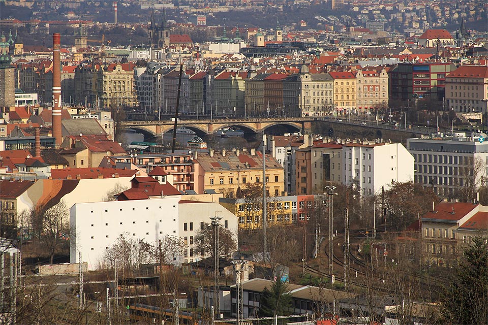 Pohled na severní zhlaví <a href=/Tema/Praha-Sm%C3%ADchov%20%28%C5%BEst%29>smíchovského nádraží</a> a Palackého most. Z levého břehu pomalu mizí jeho jedinečný průmyslový charakter.