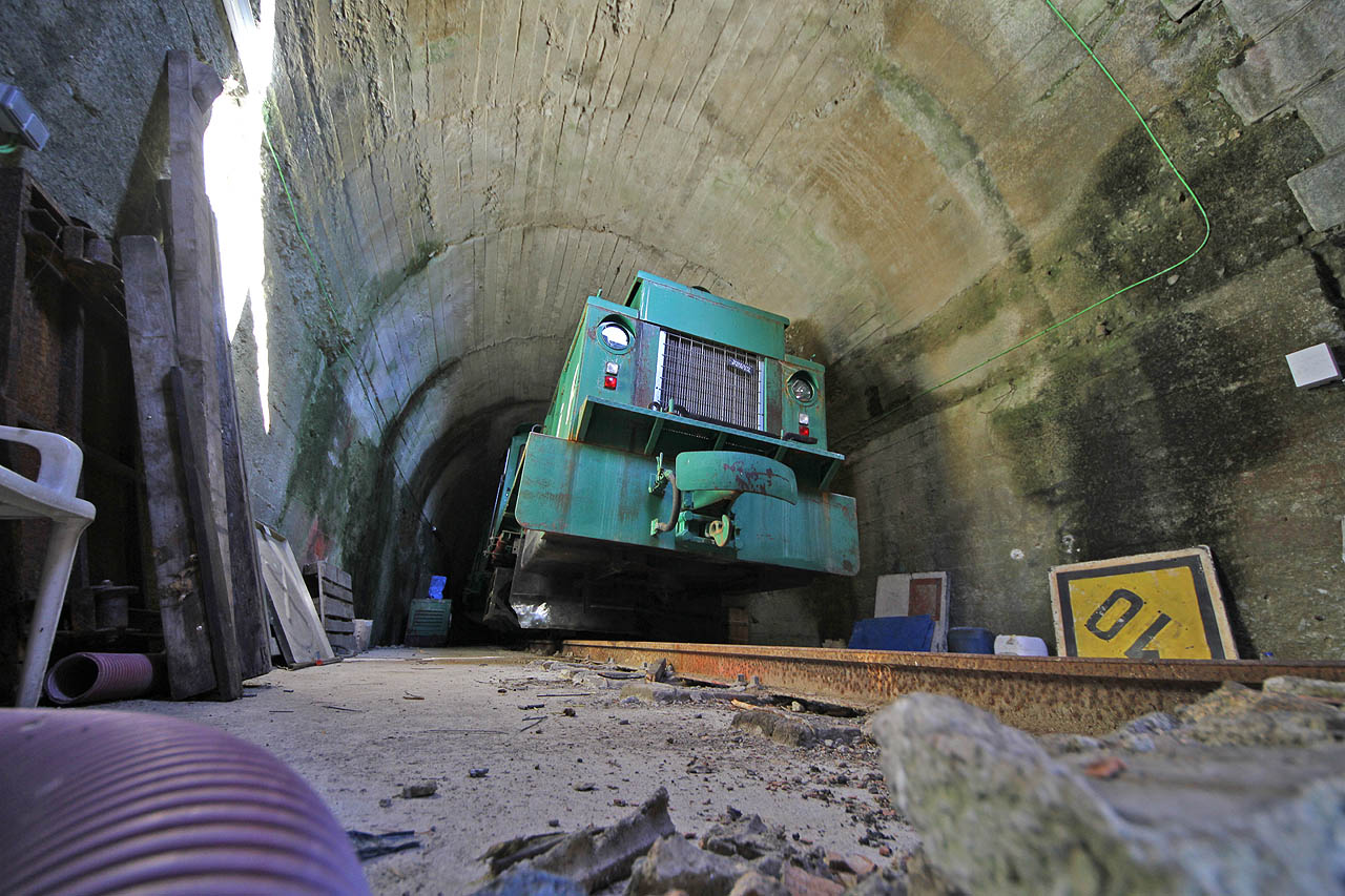 Po poledni jsem se přesunul místním vlakem (říkají jim tu cercancias) do stanice Cercedilla, kde jsem měl najitý autobus nahotru do průsmyku Puerto de Cotos (úžasných 1830 m), kde končí úzekokolejka pohořím Navacerrada. Původně měla dráha pokračovat na severní stranu hor, tunel skrze průsmyk ale nebyl nikdy dostavěn a tak jeho slepá polovina slouží jen jako depo pro zelený lokotraktor. Fotku jsem musel pořídit foťákem prostrčeným pod vraty.