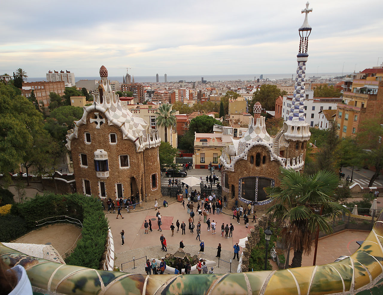 Pohled na vstupní prostor parku Güell, ve kterém Gaudí realizoval řadu zahradních staveb pro svého mecenáše textilního továrníka Güella. Na Barceloně je krásné, jak se od moře šplhá do strmých svahů nad pobřežím a čím výše člověk vystoupá, tím zajímavější místa objeví. V dálce je vidět jeřáb pracující na stavbě Sagrady Famílie i barcelonská okurka.