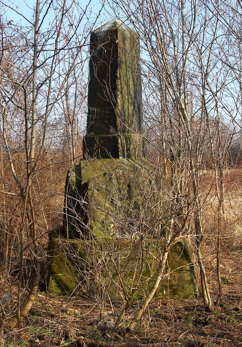 Čtevrhranný obelisk je zasazen v masivní základně z kyklopských kamenů.