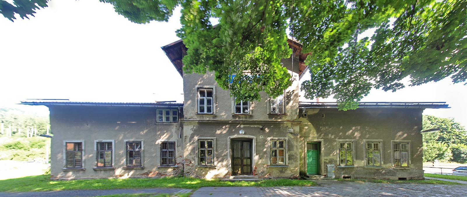 Staniční budova při pohledu od obce a silnice. Špaletová okna prozrazují, že jde o budou na poměry lokálek spíše starou, podle typového vzoru vystavěnou v roce 1871.
