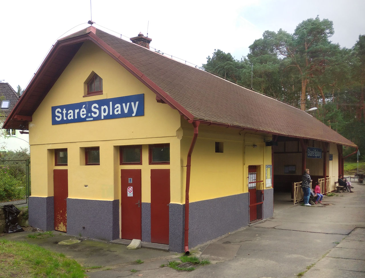 Na fotografii pořízené v roce 2021 z projíždějícího vlaku je vidět budova zastávky Staré Splavy s otevřenou čekárnou pro cestující.