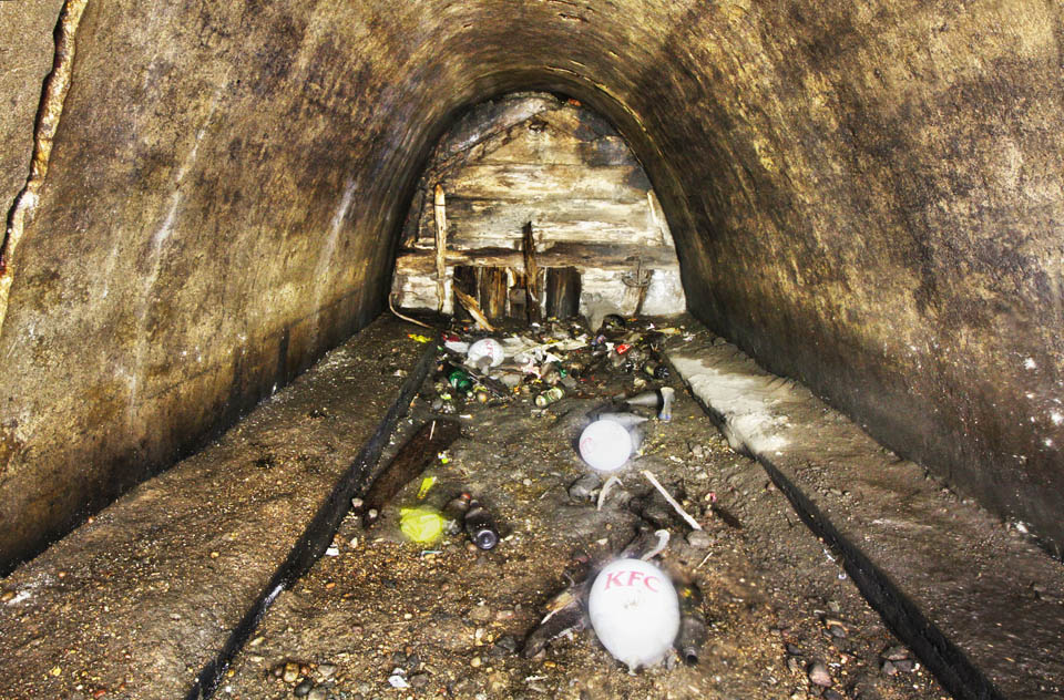 Samotný tunel pak končí pod křížením s ulicí Праспект Пераможцаў. Za betonovou zdí, ještě olepenou tlejícími zbytky dřevěného bednění z roku 1984, se dnes prohání soupravy metra na červené lince (Аўтазаводская). Balónky jasně ukazujáí, kde přesně se v podzemí nacházíme…